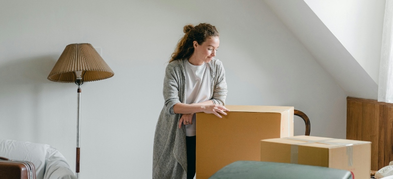 A woman standing near boxes and thinking about how fall is the perfect season for moving.