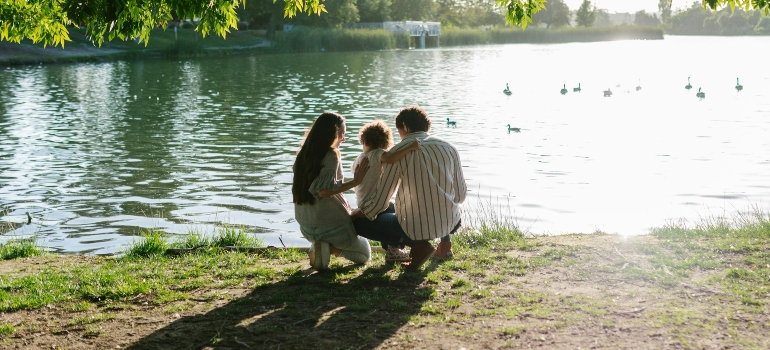 A man and a woman with their child standing near a river, discussing how fall is the perfect season for moving.