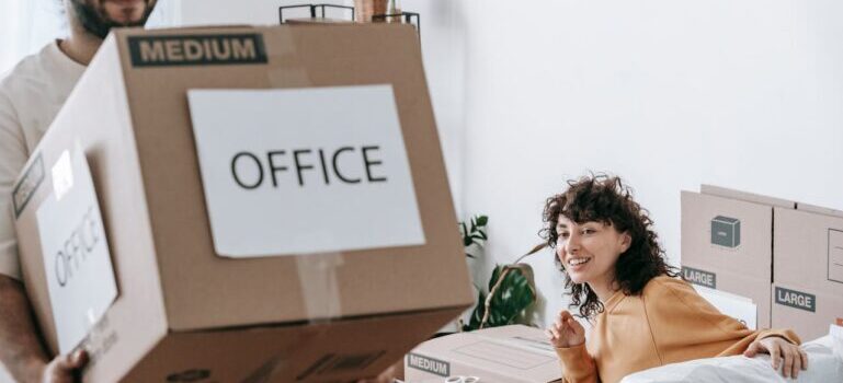 man holding a box and a woman sitting and looking at him while waiting for commercial movers in St. Louis