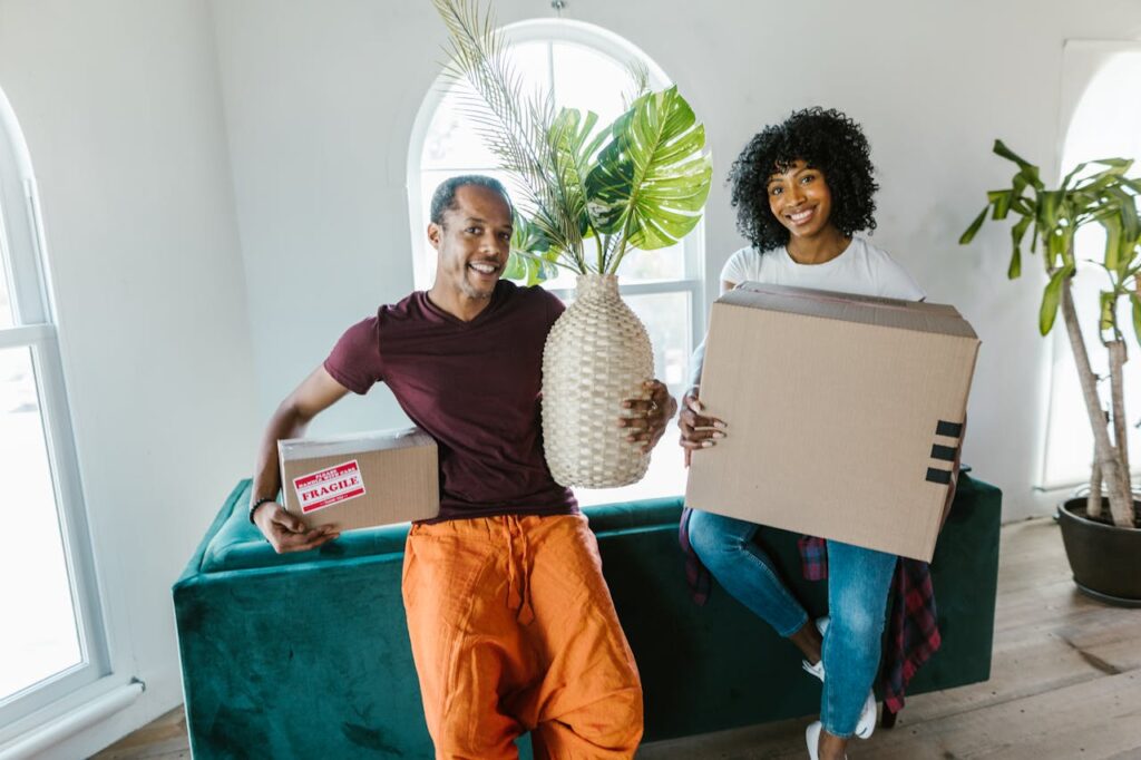 man holding a box and a plant and woman near him holding a box