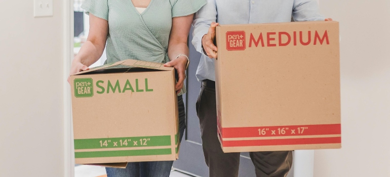 A man and a woman are holding carton boxes and talking about movers in Ballwin.