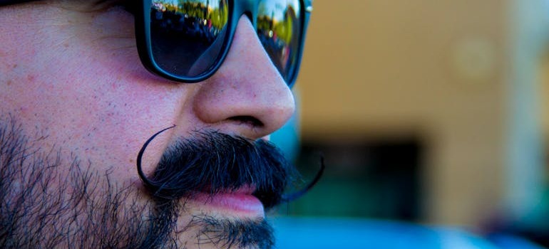 A man with a moustache wearing sunglasses